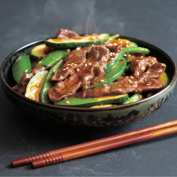 Beef stir fry with zucchini and snap peas in soy glaze — one of the quick and healthy summer dinner recipe ideas.